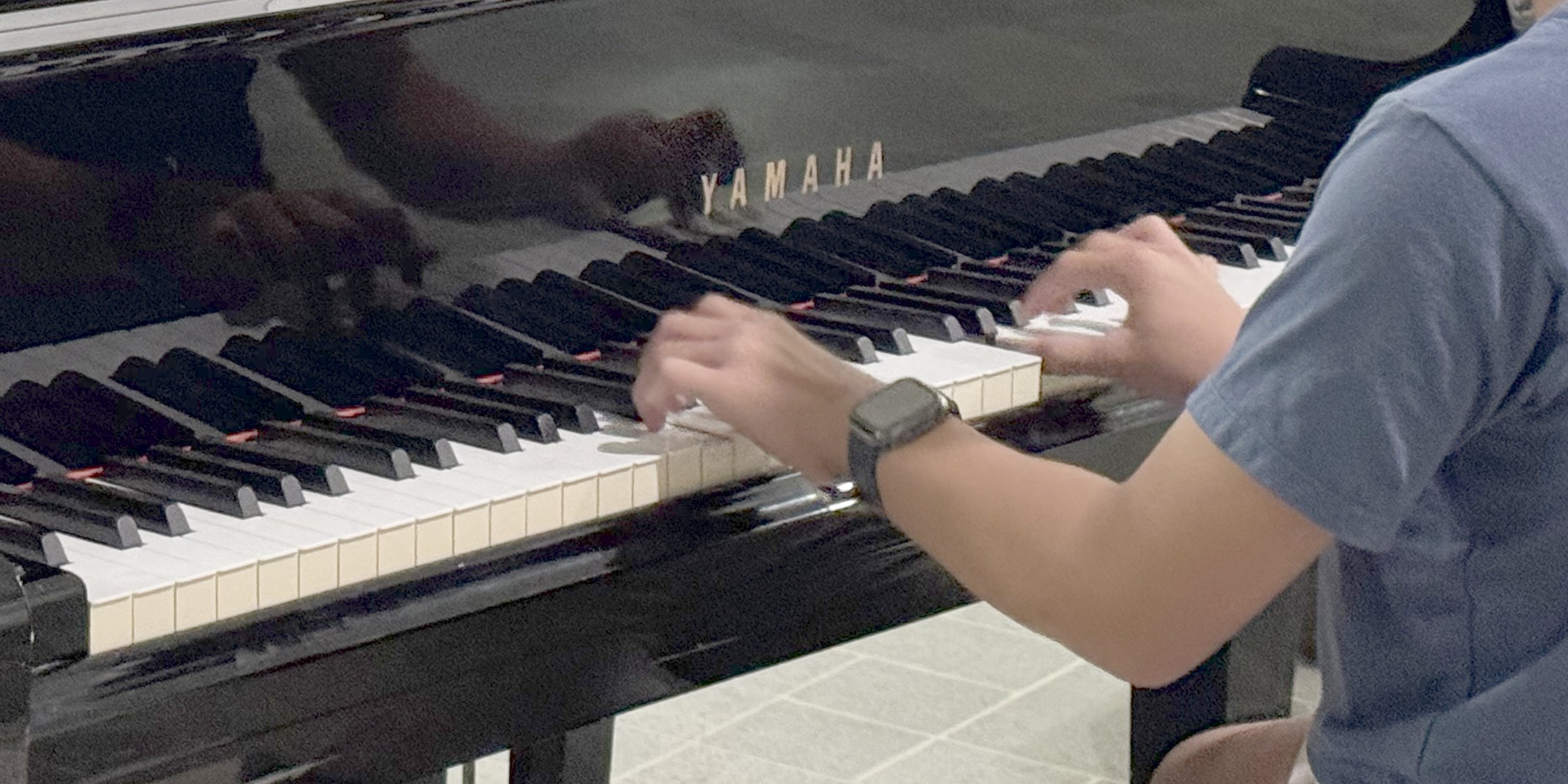 A student's hands on the keys of a grand piano.