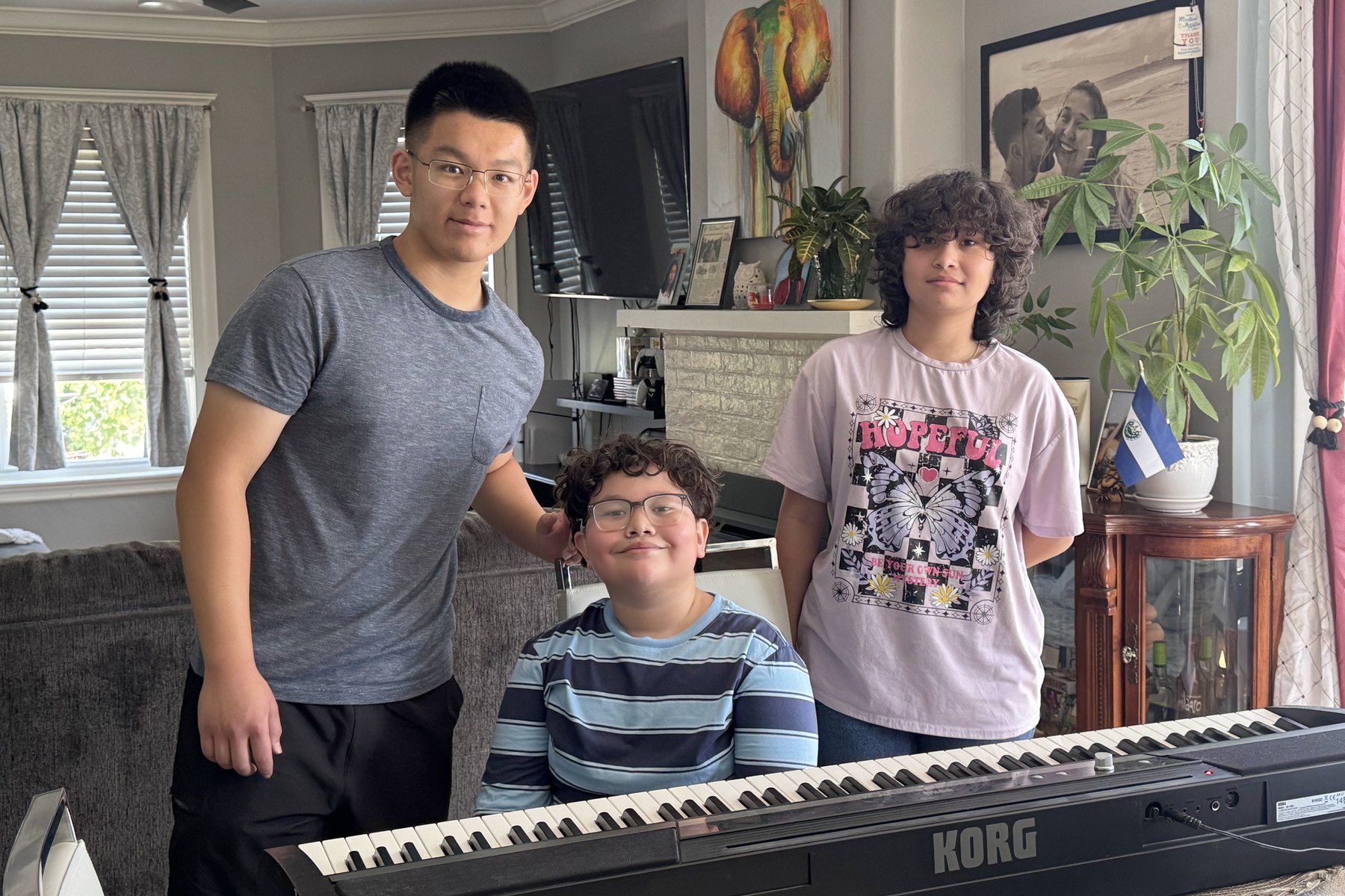 Three young people at home with the keyboard, set up and switched on.