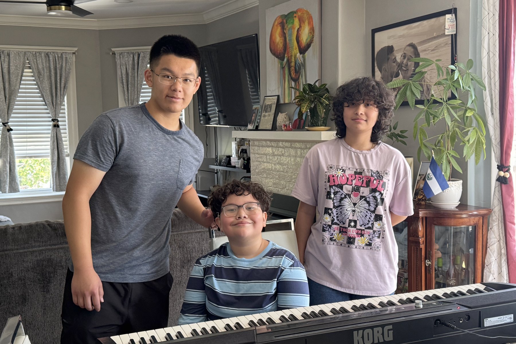 Three young people at home with the digital piano that has just been delivered to them.